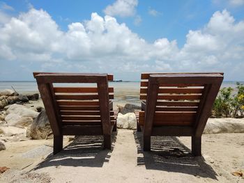 Chair on beach against sky