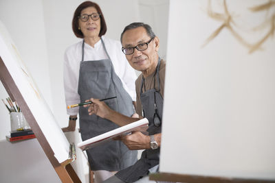 Portrait of couple painting on canvas at home