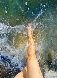 Low section of man splashing water in sea