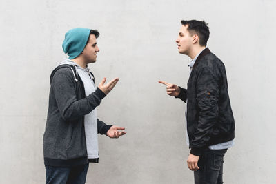 Side view of young man standing against wall