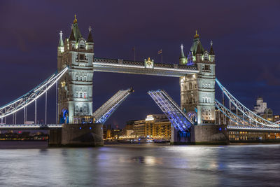 Illuminated bridge over river at night