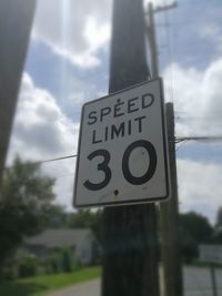 Close-up of road sign against sky