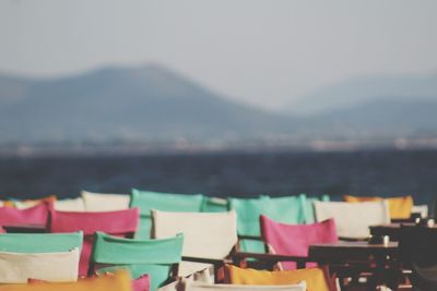 Multi colored chairs at beach against sky