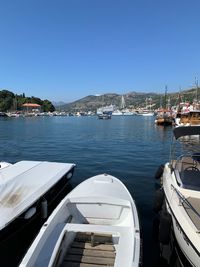 Sailboats moored at harbor against clear sky