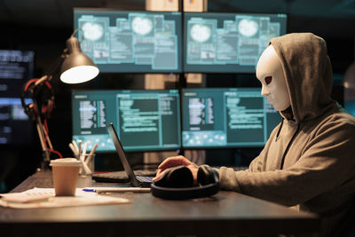 Rear view of woman using laptop on table