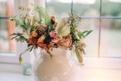 Close-up of dry flowers in vase on window sill 