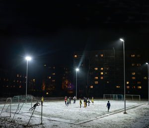 Players practicing on soccer field in stadium at night