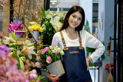 Portrait of smiling florist with flowers standing in store