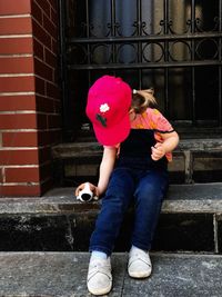 Full length of woman sitting against brick wall