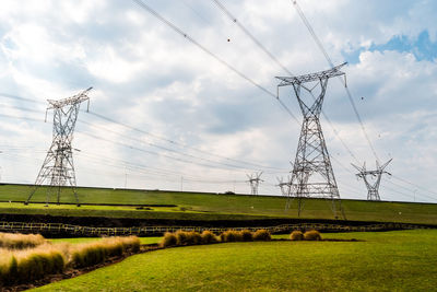 Electricity pylon on field against sky