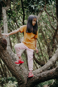 Full length of woman standing on tree trunk