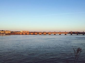 Bridge over river against clear blue sky