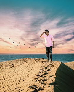 Man standing on beach against sky during sunset