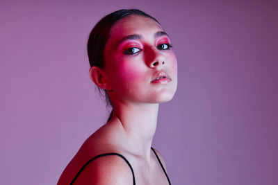 Portrait of young woman against purple background