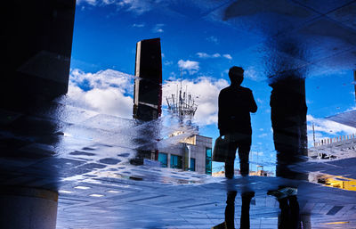 Man standing against blue sky in city