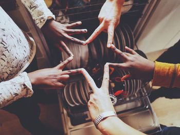Cropped image of friends making star shape over dishwasher in kitchen
