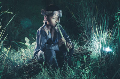 Boy playing flute on field at night
