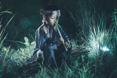 Young woman sitting on field at night