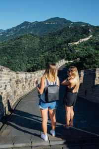 Full length of friends standing on mountain against clear sky