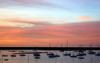 Boats moored at harbor during sunset