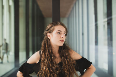 Young woman looking away while standing in building