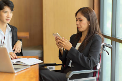 Young woman using phone while sitting on table