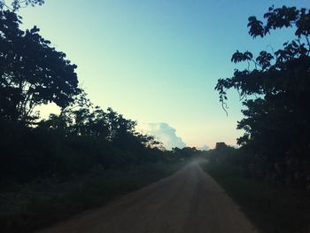 Road amidst trees against sky during sunset