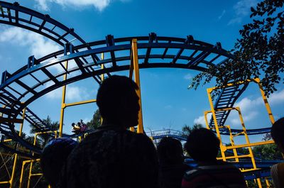 Rear view of people at amusement park against sky