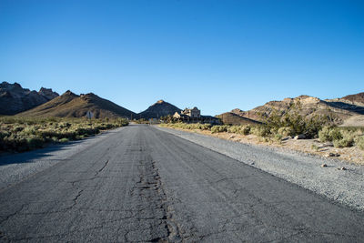 Road amidst mountains against clear blue sky