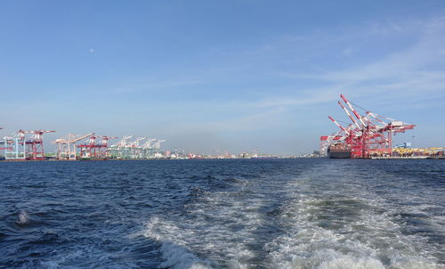 Cranes at commercial dock against sky