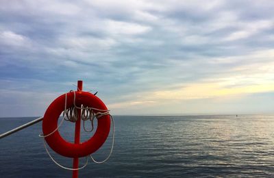 Red boat on sea against sky during sunset