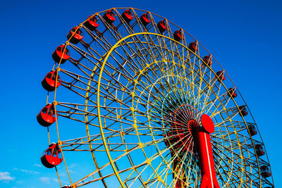 Low angle view of ferris wheel against clear blue sky