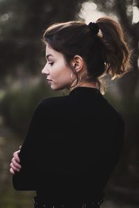 Rear view of thoughtful young woman standing outdoors