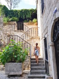 Rear view of woman moving up on staircase by building