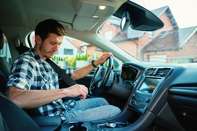 Midsection of man using mobile phone while sitting in car