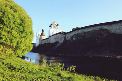 Building by river against clear blue sky