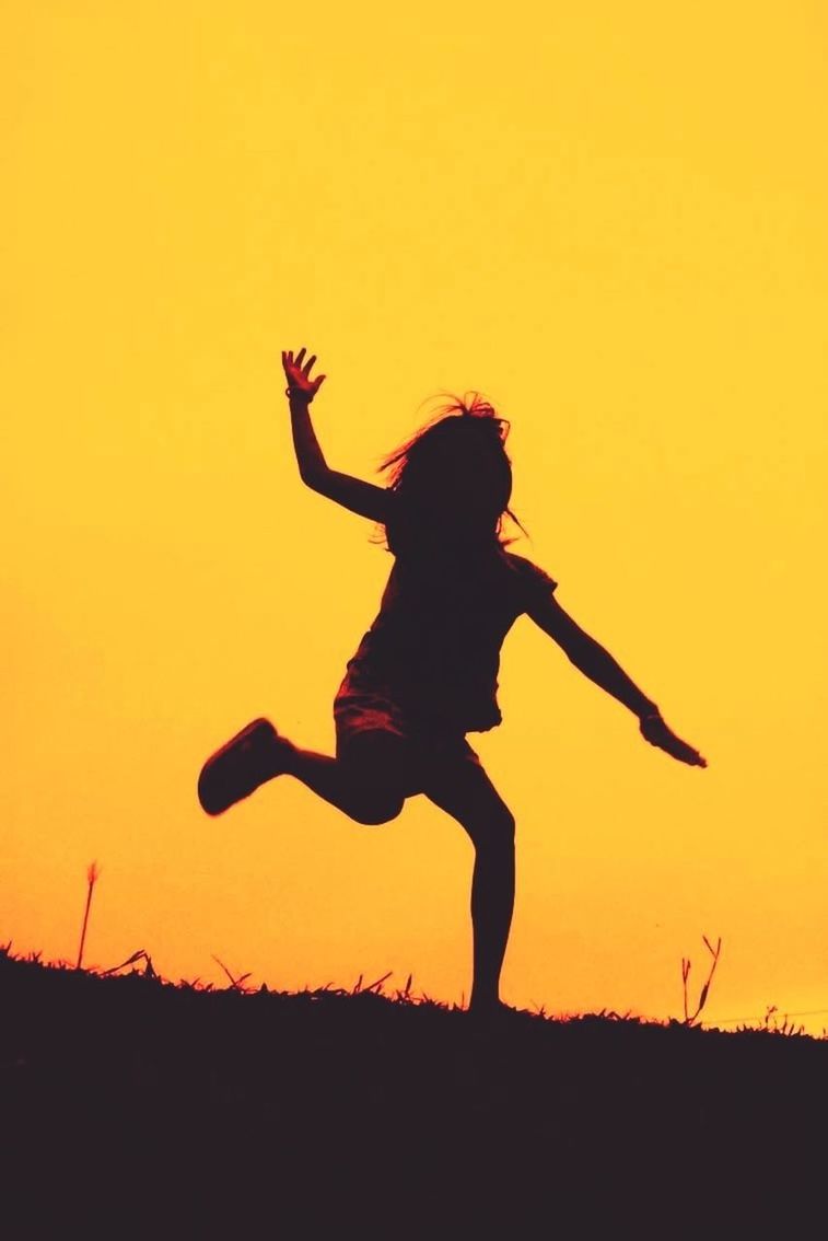 sunset, silhouette, leisure activity, lifestyles, full length, orange color, enjoyment, mid-air, arms raised, fun, arms outstretched, field, copy space, standing, jumping, carefree, clear sky, freedom