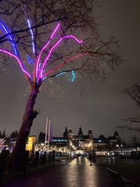 Illuminated city by river against sky at night