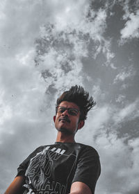 Low angle view of young man standing against sky