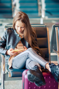 Girl using mobile phone while sitting at airport