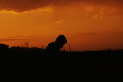 Silhouette man on field against sky during sunset