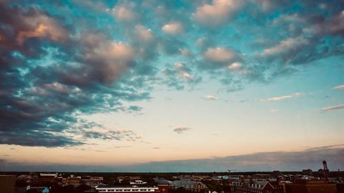 Cityscape by sea against sky during sunset