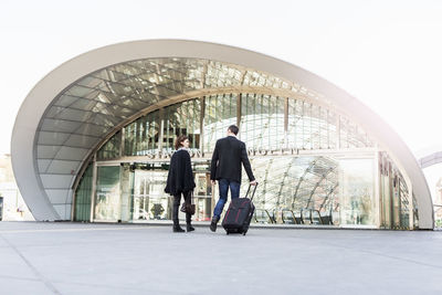 Rear view of business people talking while entering railway station