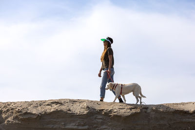 Young woman walking with her dog in a desert