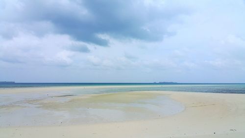 Scenic view of beach against cloudy sky