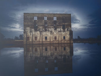 Reflection of building in lake against sky