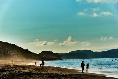 Silhouette people on beach against sky in the morning