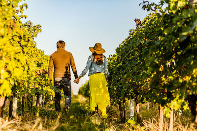 Rear view of couple walking on field against sky