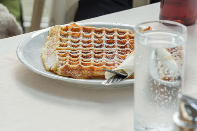 Close-up of waffle with drink on white table