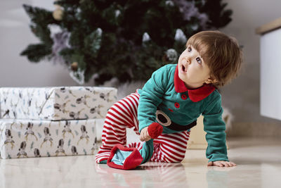 A little 12-month-old christmas elf with a christmas tree and gifts